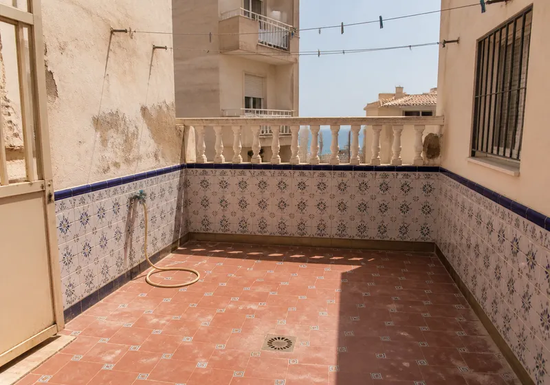 Patio de bloque en Torrevieja con grifo exterior y azulejo desgastado por el ambiente costero