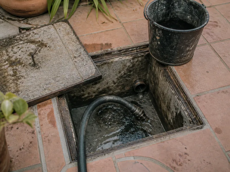 Arqueta de saneamiento abierta en un patio, sin personas